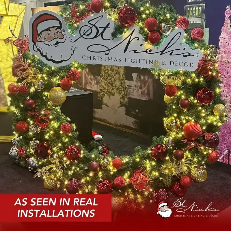 Decorative Christmas wreath with lights and ornaments, featuring St Nick's Christmas Lighting & Decor branding.