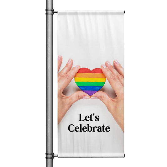 Pride pole banner featuring hands holding a rainbow heart on a white background with “Let’s Celebrate” message