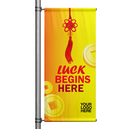 Lunar New Year pole banner with yellow gradient background featuring red Chinese knot, gold coin accents, and “Luck Begins Here” message