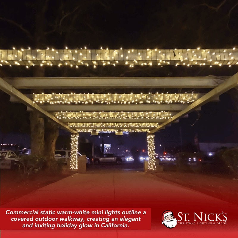 A covered walkway in Culver City glows with warm white mini lights wrapped across overhead beams and support columns.