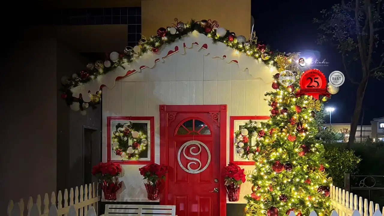 Decorative gingerbread house with Christmas lights and a tree at night.