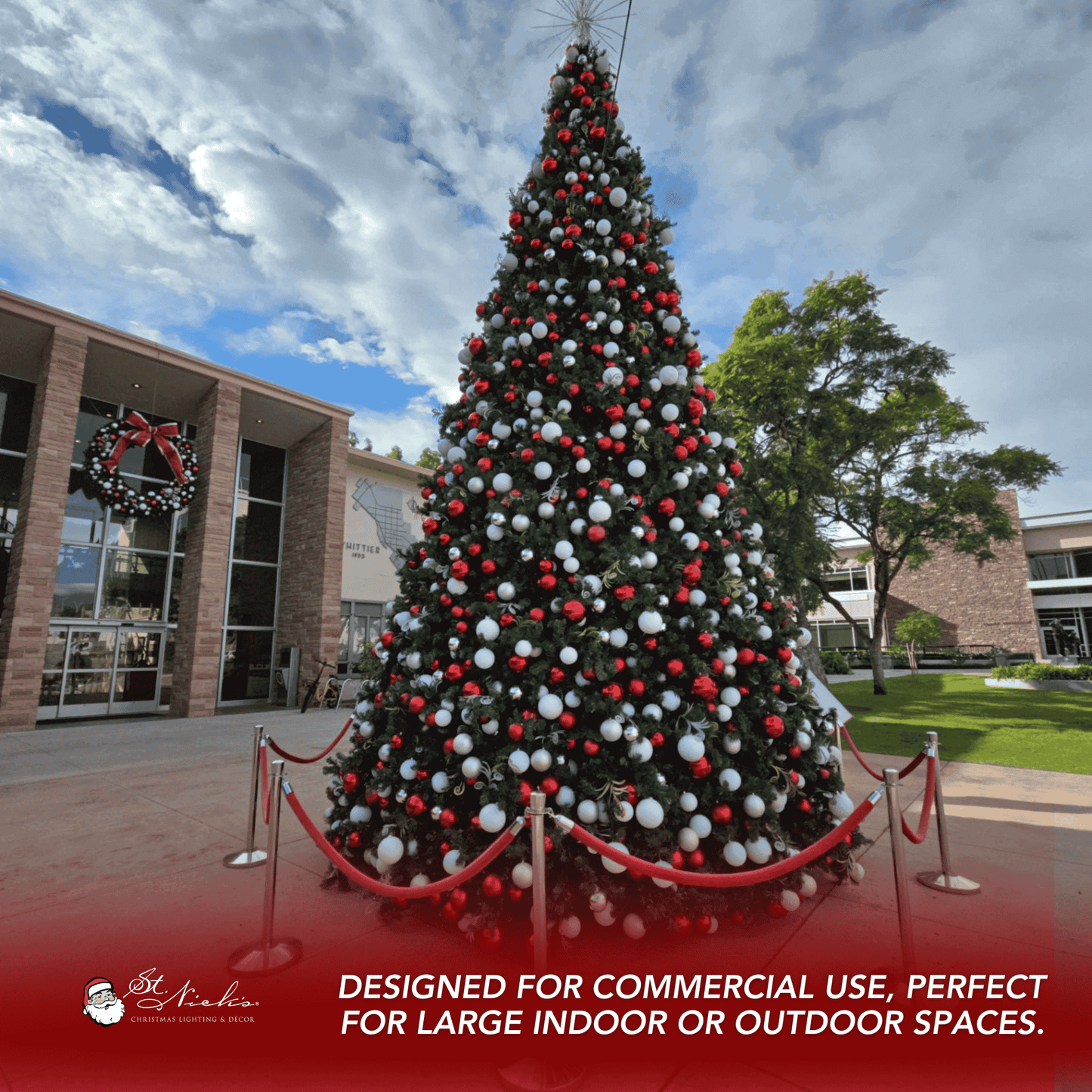 Decorated Christmas tree with red and white ornaments in front of a building.