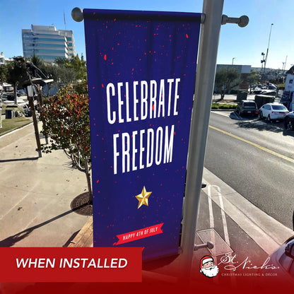 Celebrate Freedom 4th of July pole banner installed along city street for patriotic Independence Day décor