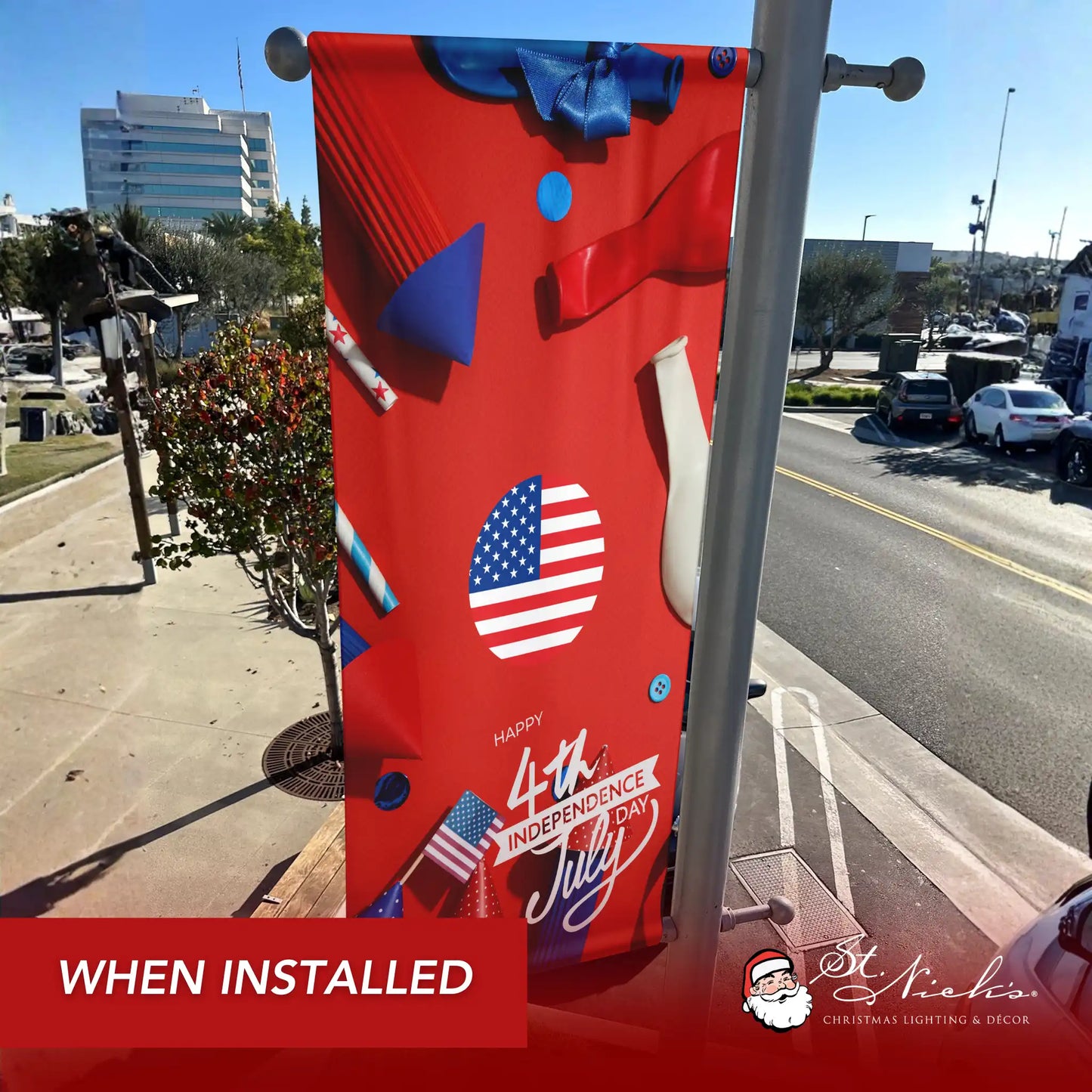 Happy 4th of July red party pole banner installed along city street for patriotic Independence Day décor