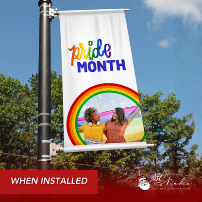 Pride Month photo pole banner shown installed on city street pole with rainbow graphic and inclusive message