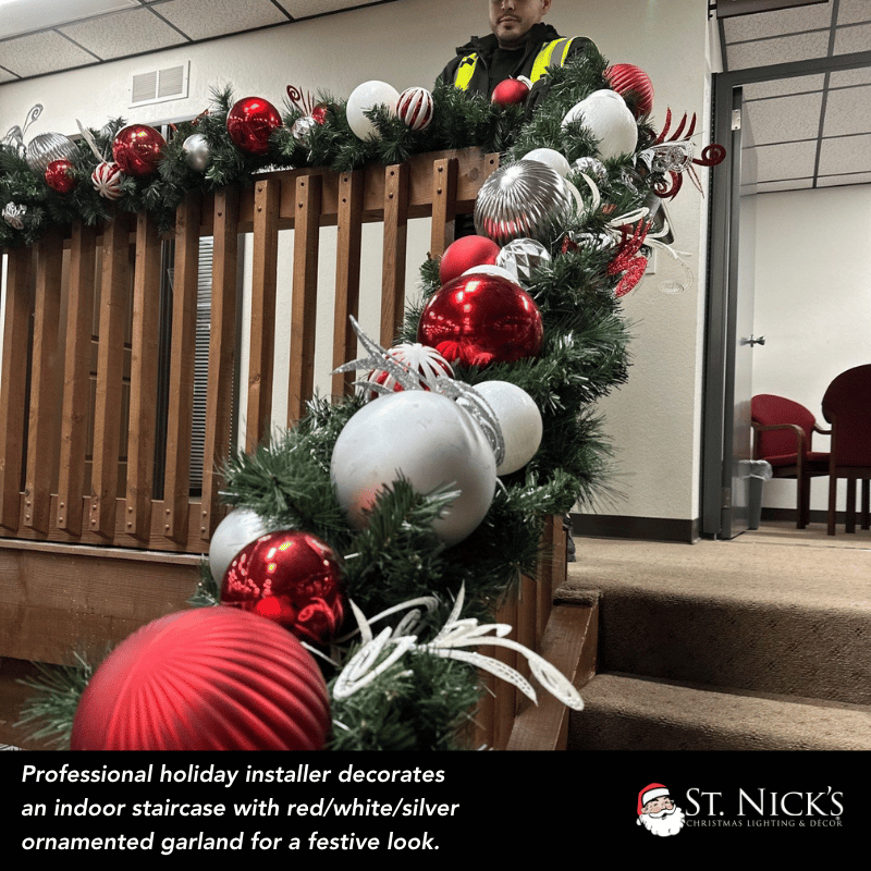 Red, white, and silver ornamented garland decorates an indoor staircase during a professional holiday installation in Jurupa Valley.