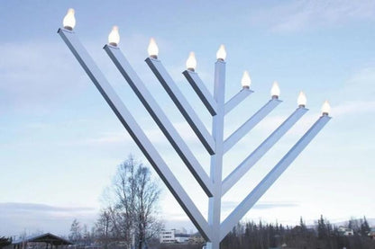 Large outdoor menorah with lit candles 