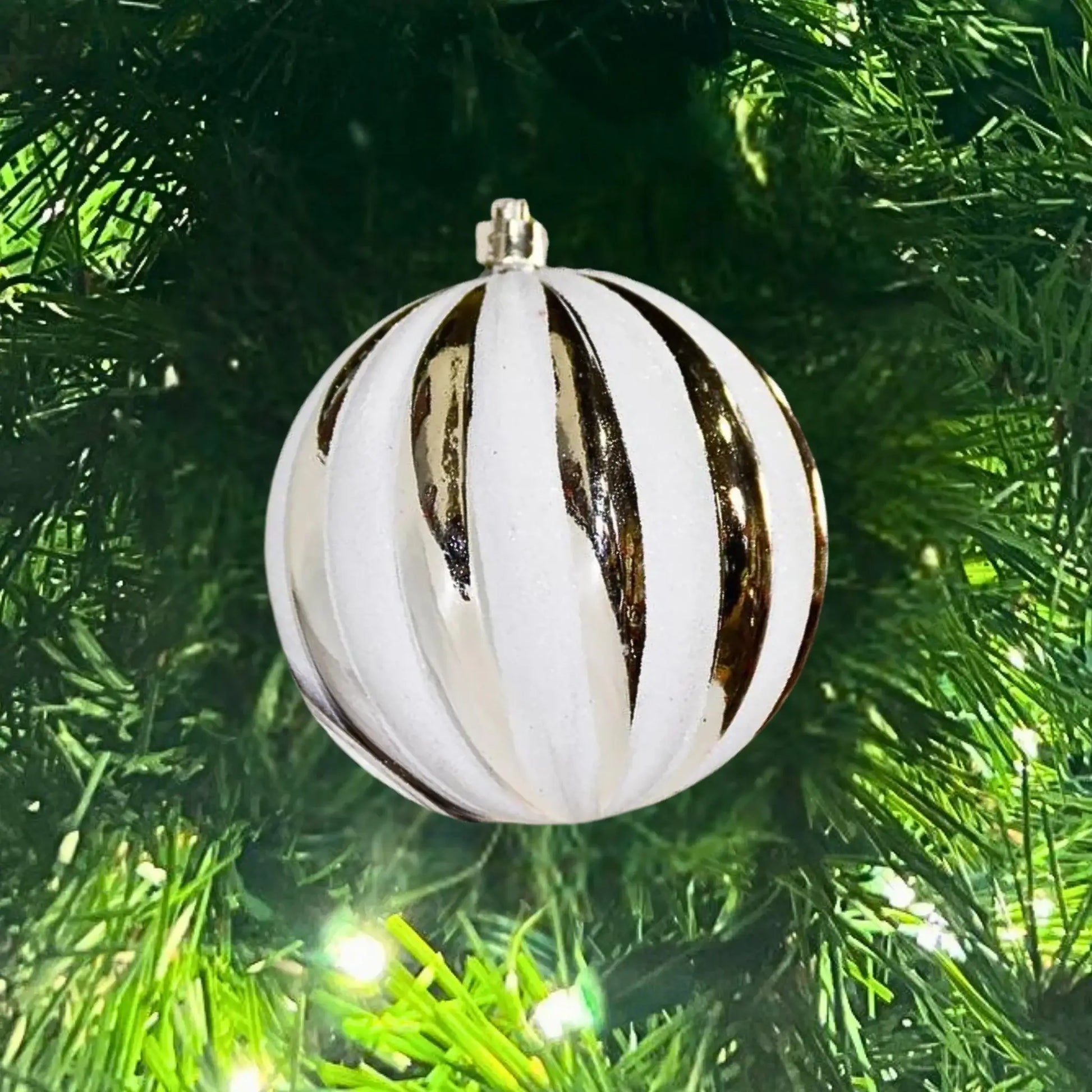 Decorative white and gold striped ornament on a Christmas tree.
