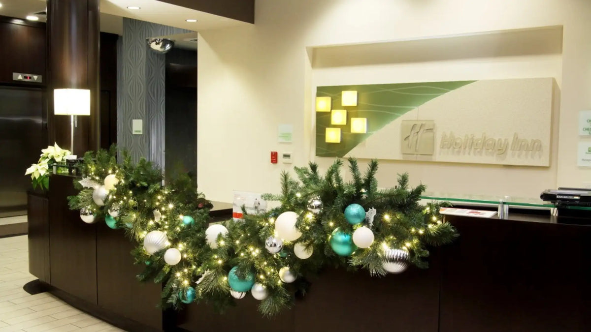 Decorative Christmas garland with lights and ornaments on a reception desk in an office setting.