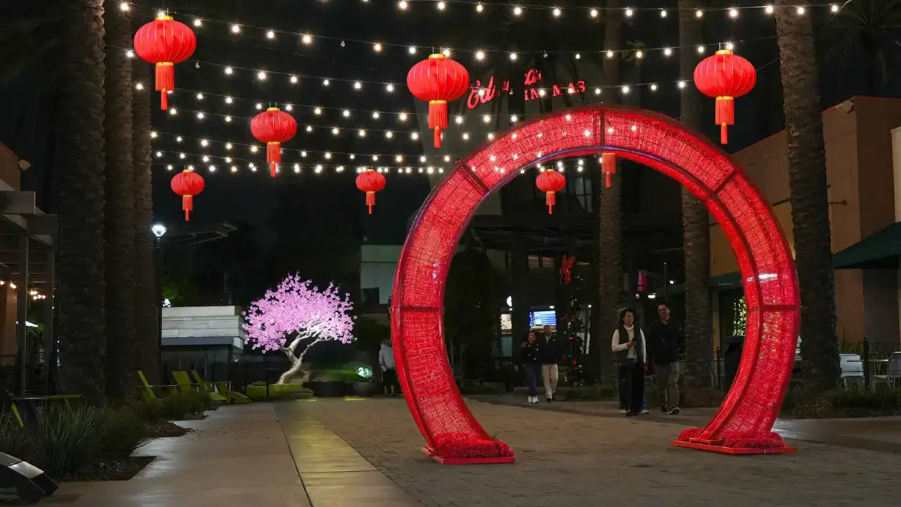 Decorative red archway with hanging lunar new year lanterns at night in an urban setting.