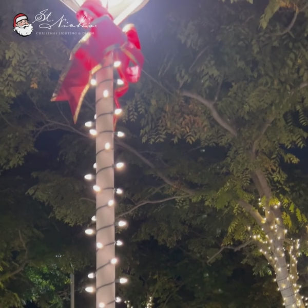 Christmas bow red nylon with silver lining mounted on large decorated wreath with lights and ornaments in indoor display