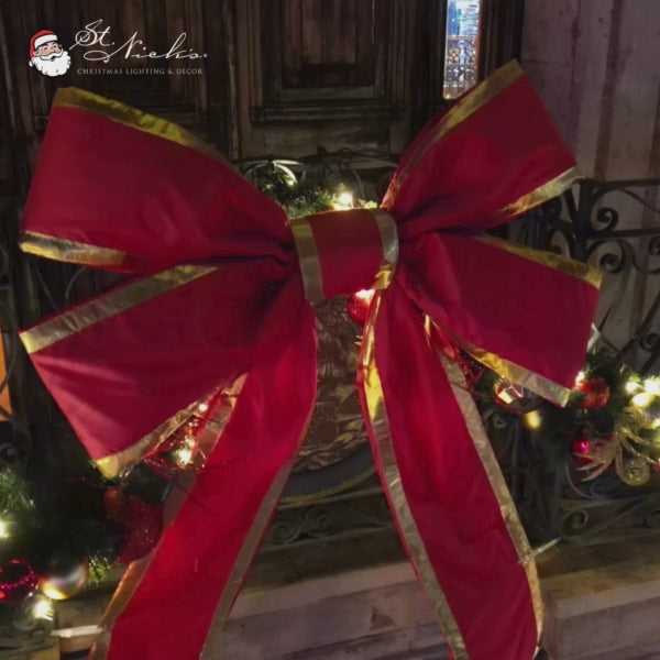Christmas bow red nylon with gold lining mounted on decorated wreath with lights and ornaments for outdoor holiday display